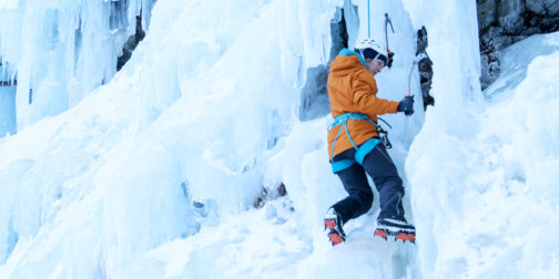 Frau probiert das Eisklettern gesichert im Nachstieg.