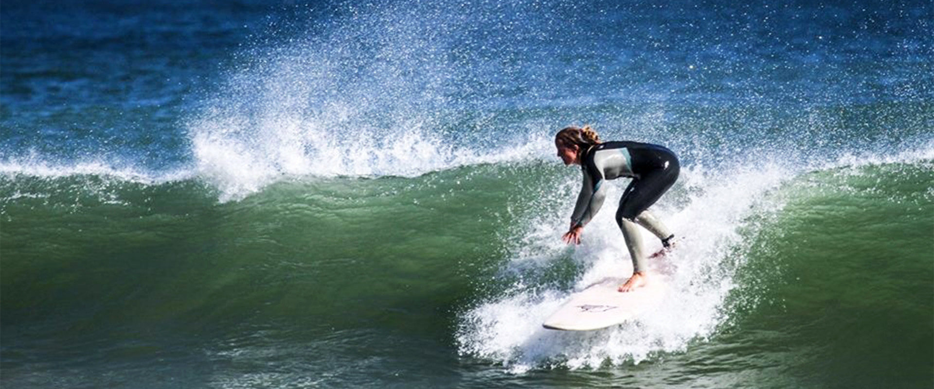 Stefanie Schider surft auf einer Welle am Meer.
