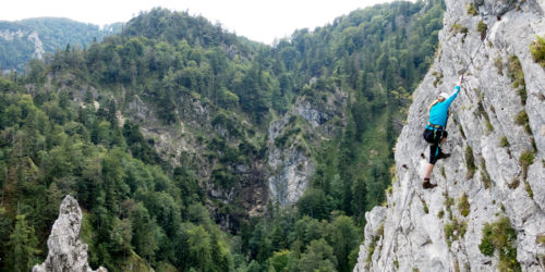 Klettersteiggeherin auf steiler Felswand