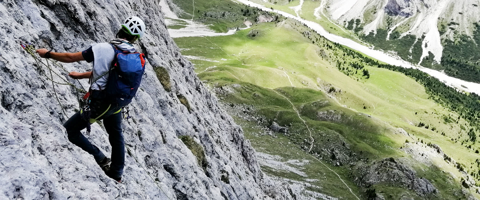 Alpinklettern in grüner Almlandschaft und grauem Kalkgestein.